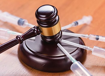 Gavel surrounded by syringes, symbolizing legal issues related to drug abuse and substance control. - Law Office Of Greg Webb