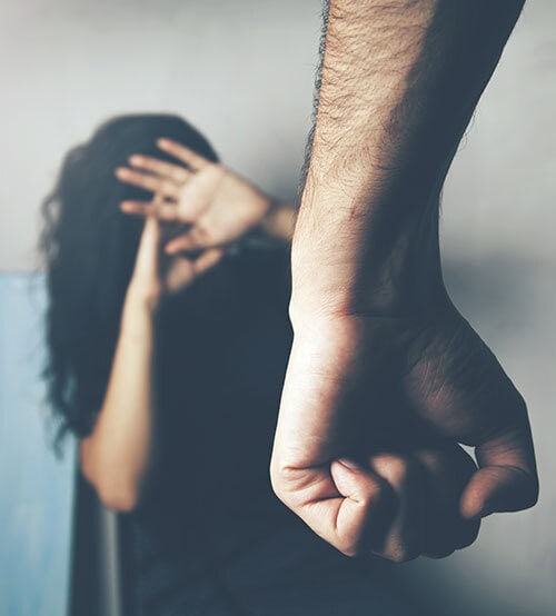 Domestic violence image showing a woman shielding herself from a raised fist, highlighting abuse and protection