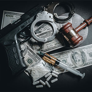 Drugs, handcuffs, and a gun, symbolizing elements of criminal defense - Law Office Of Greg Webb